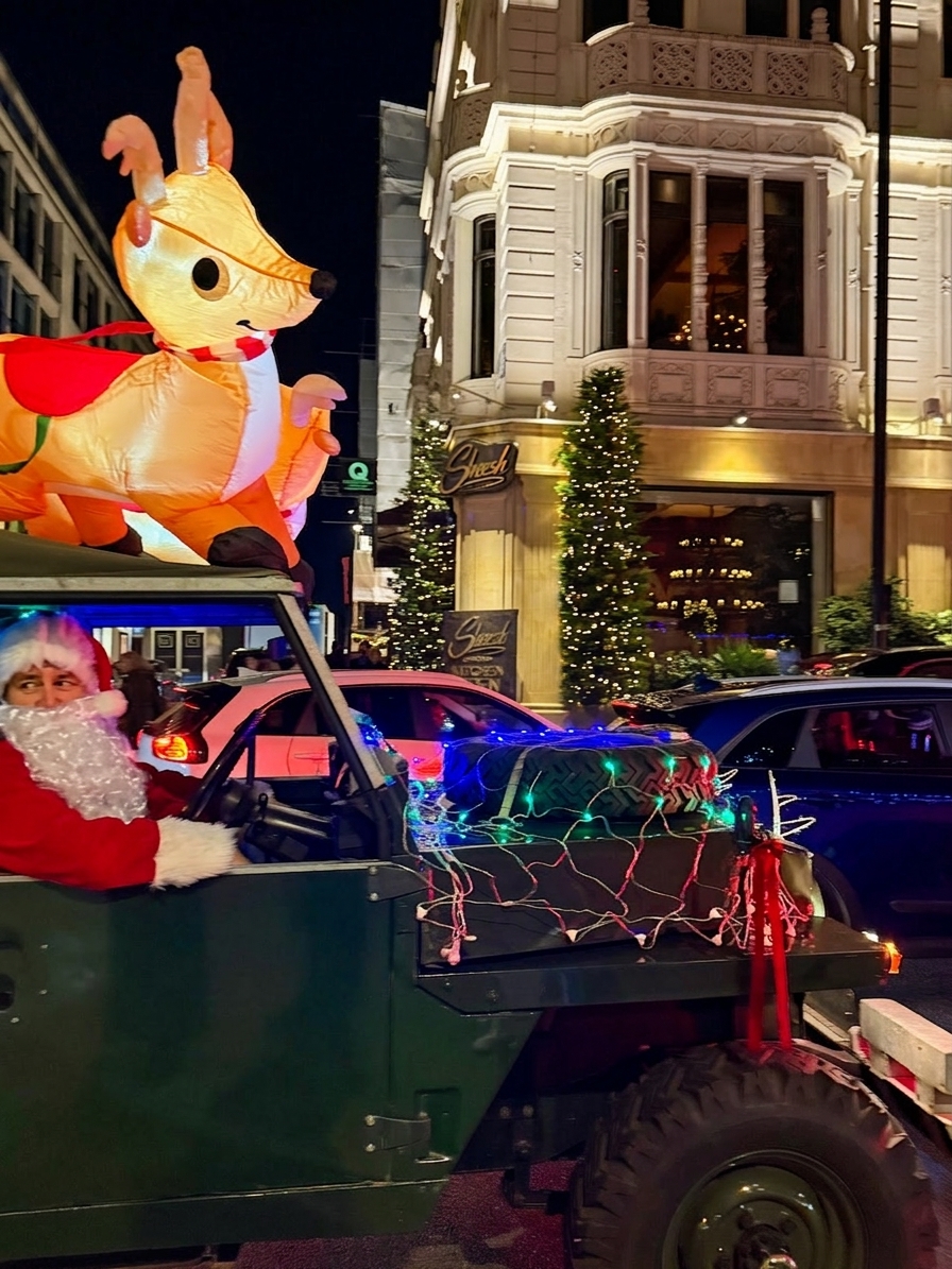 Santa Claus riding in a decorated Land Rover Defender with inflatable reindeer at Belgrave Square